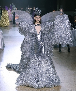 Model walking down runway with silver dress