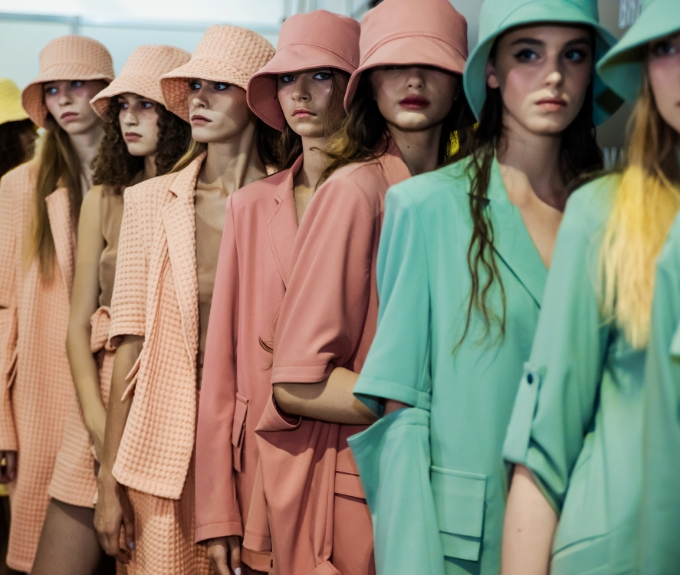 Row of fashionista with nude green, pink and orange suits and dresses